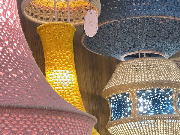 Lit crochet pendant lamps in pink, yellow and blue.