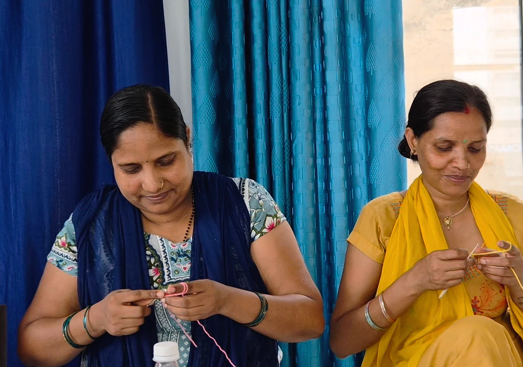 Two artisans crocheting side by side.
