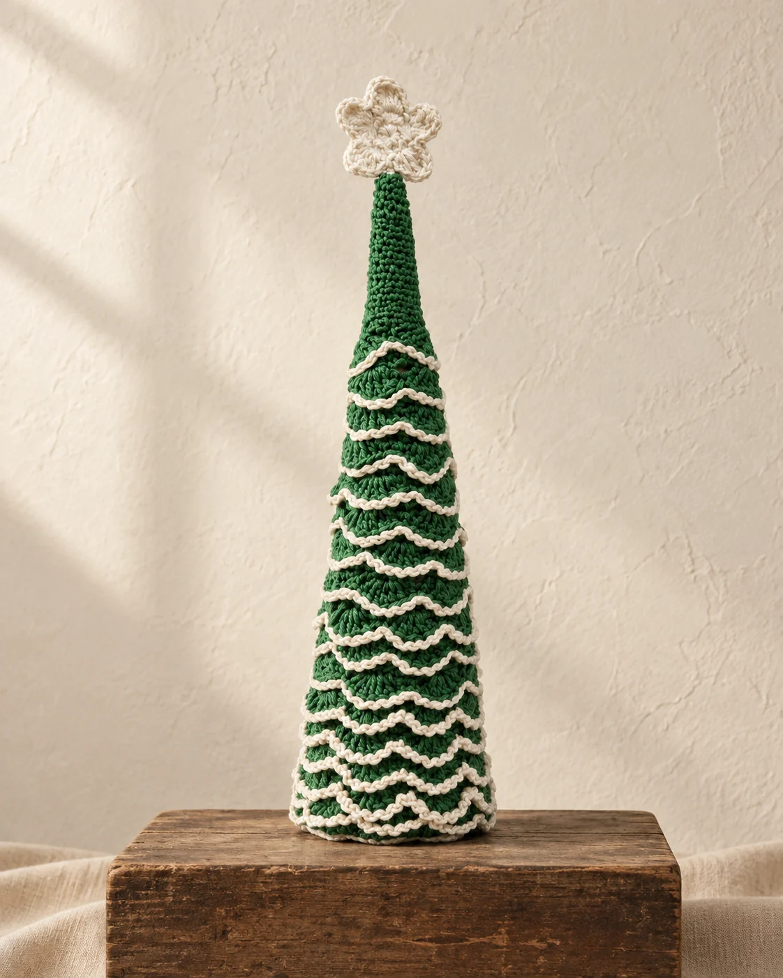 Green crochet Christmas tree with white ruffled bands and a white flower topper.