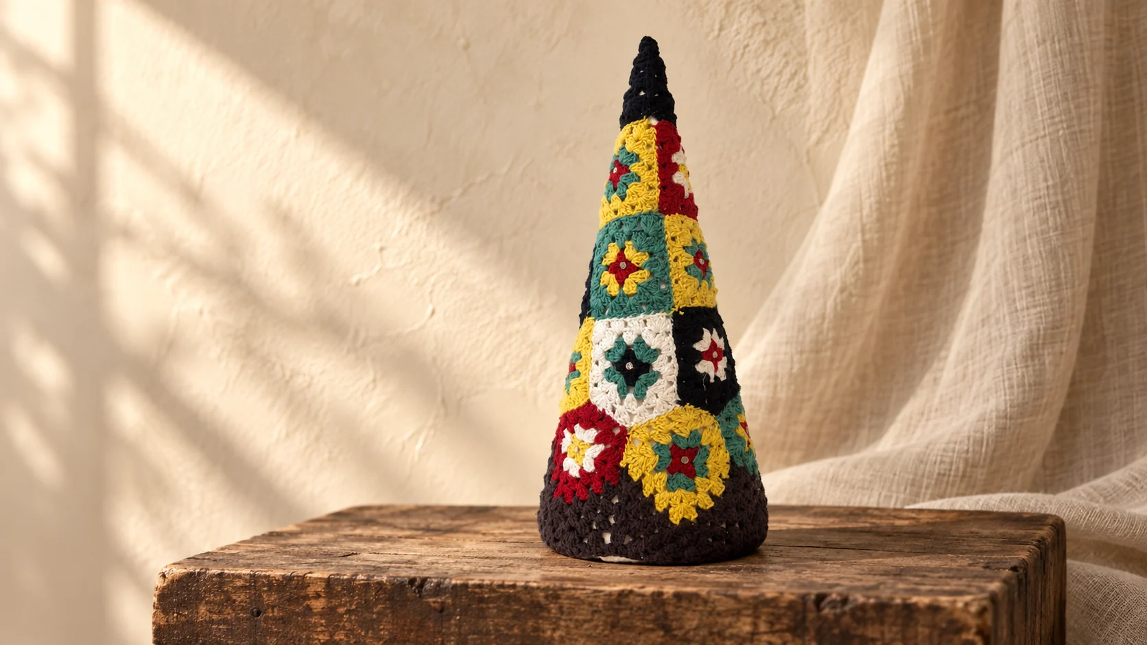Colourful patchwork crochet Christmas tree in a warm seasonal setting.
