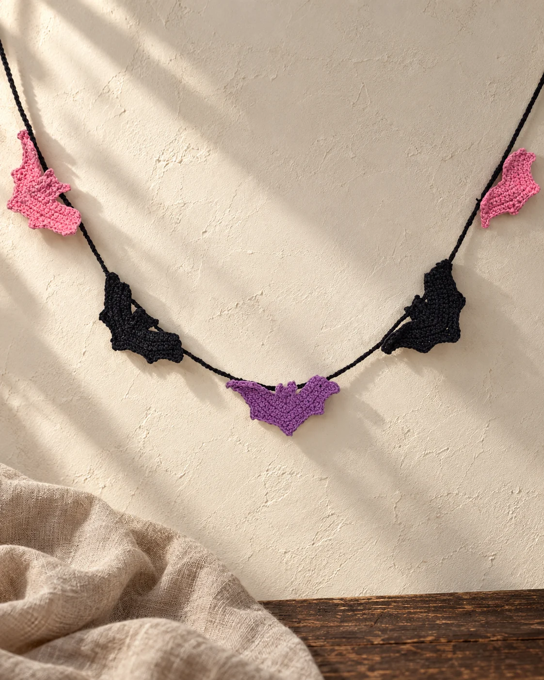 Black, purple and pink crochet bats arranged as a Halloween garland.