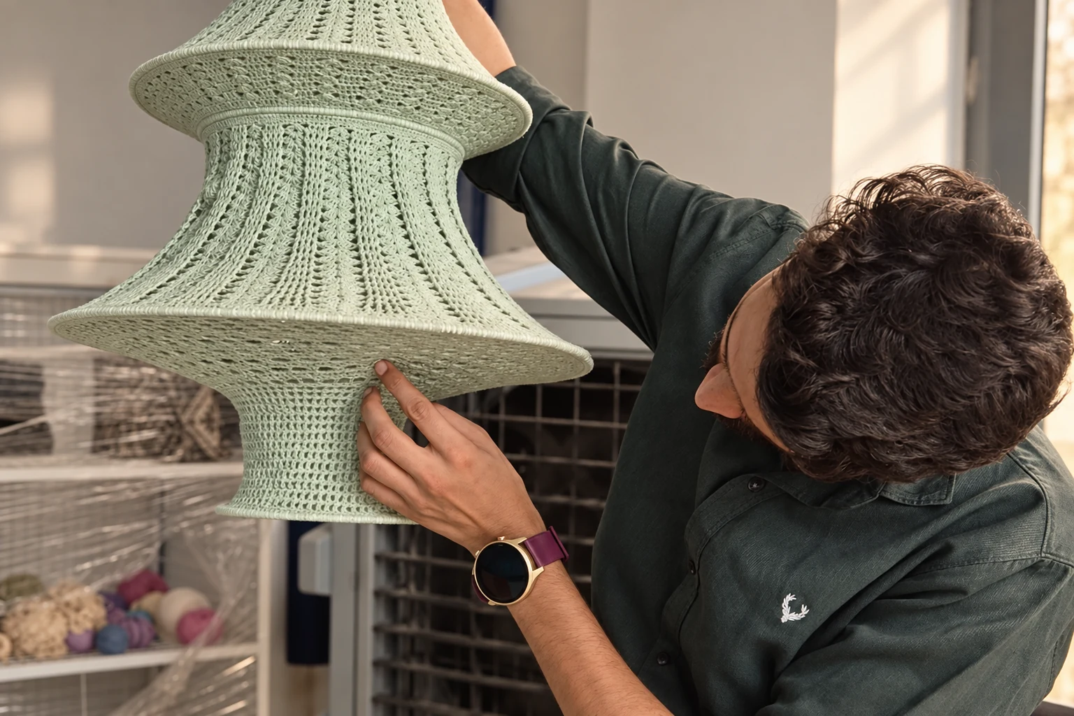A maker checking the shape and finish of a mint crochet pendant shade.