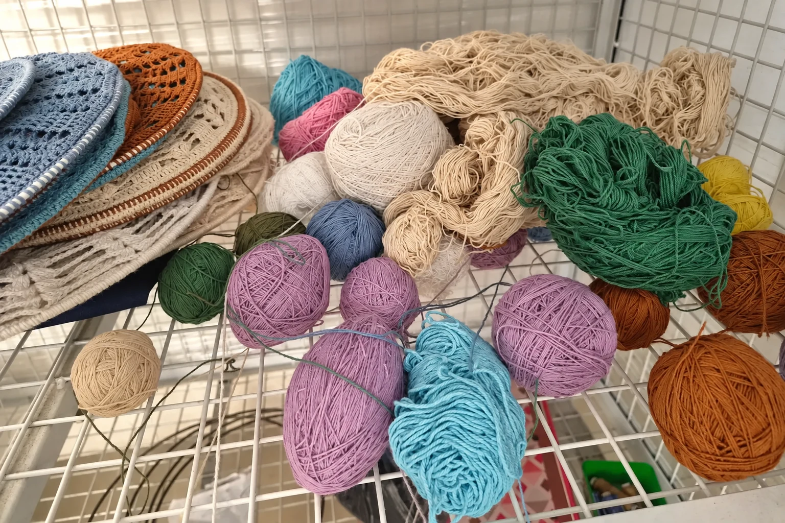Assorted cotton yarn and crochet panels arranged on wire shelving.