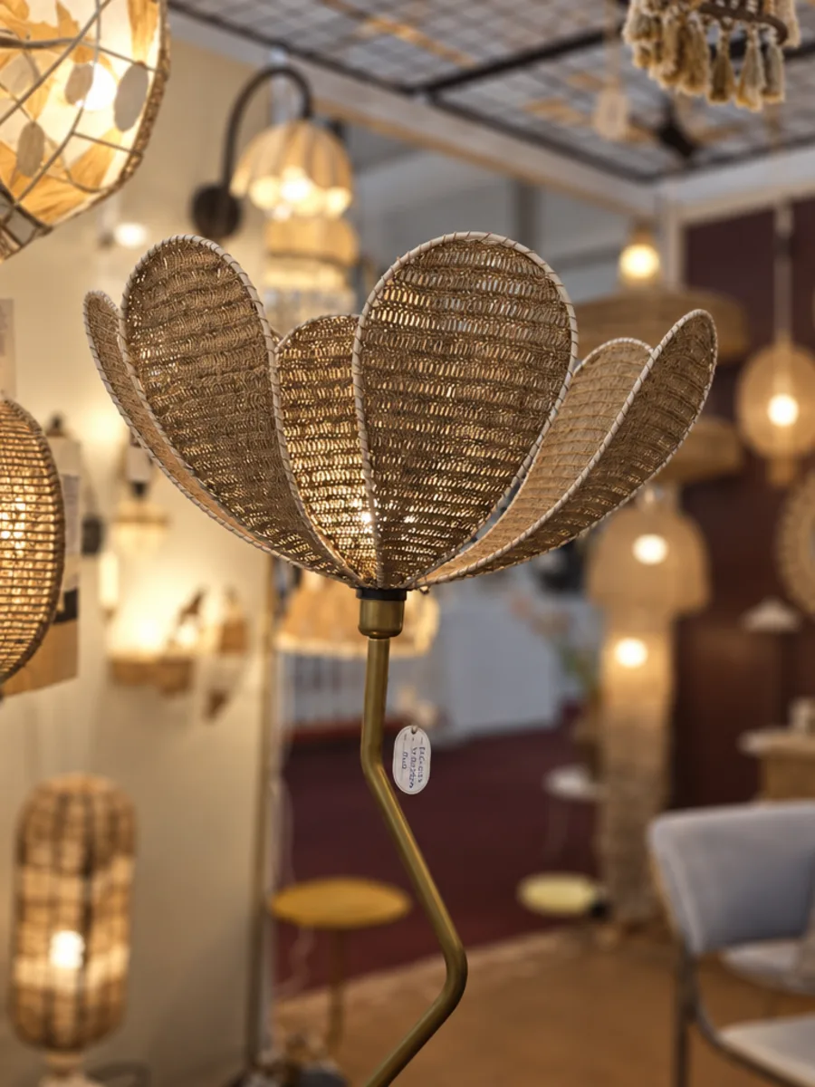 A crochet floor lamp with a petal-shaped shade, with more crochet lamps glowing behind it.