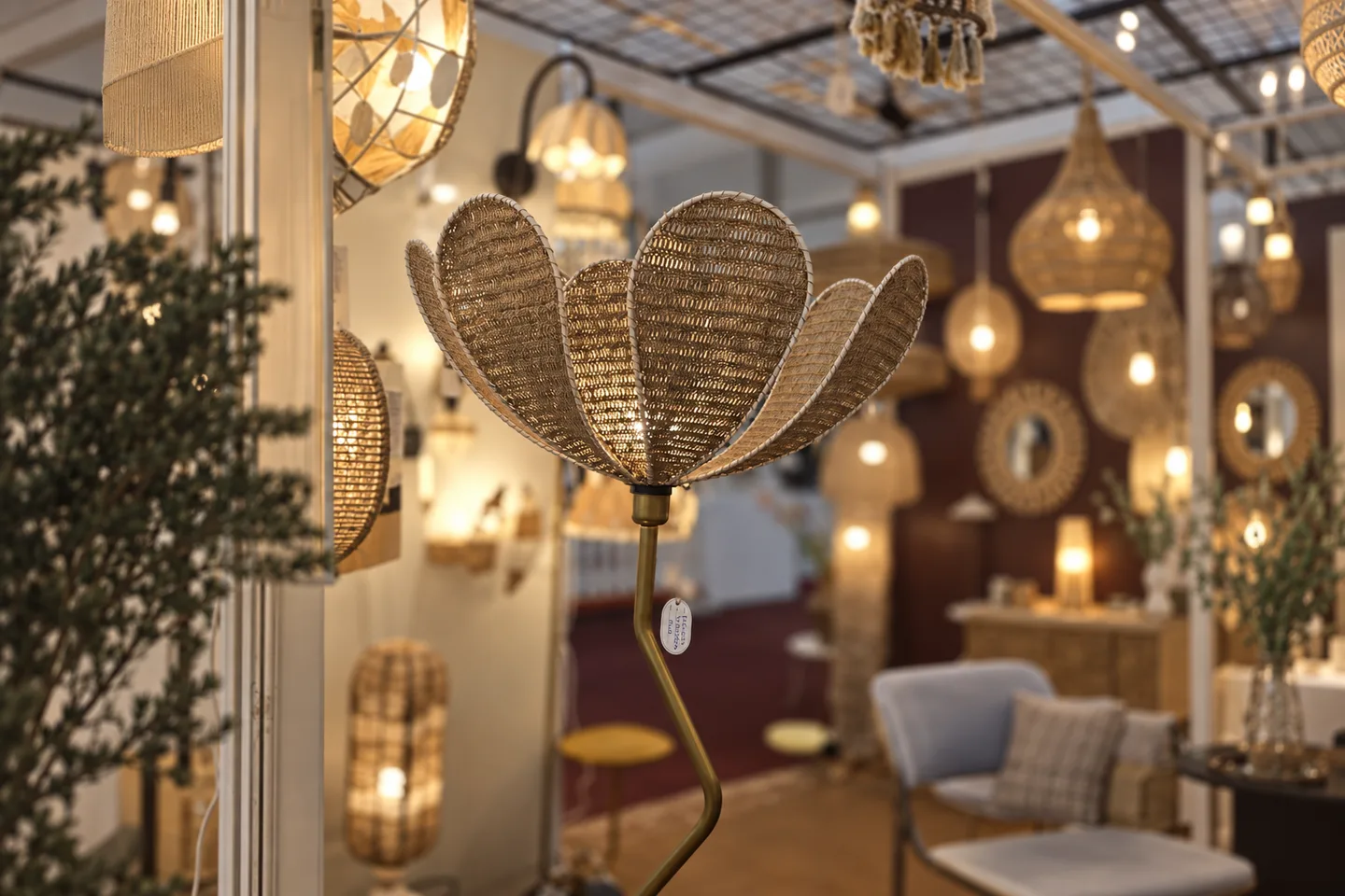 Flower-shaped woven lamp with a curved brass stem among warmly glowing lights