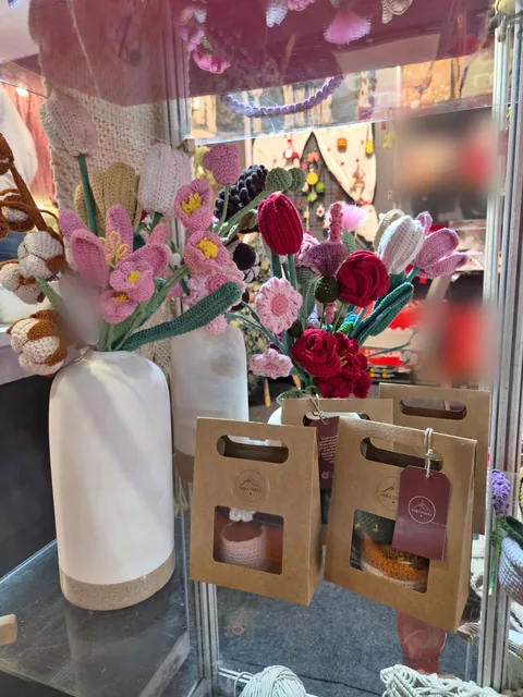 Crochet flower bouquets of tulips, roses and daisies in white vases, with kraft gift bags carrying Vera Verve tags, at our stall, Gifts World Expo 2026.