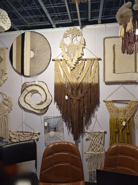 A wall of macramé at our stall, IHGF Delhi Fair Autumn 2026: a cream and brown ombré wall hanging, round woven panels and smaller hangings.