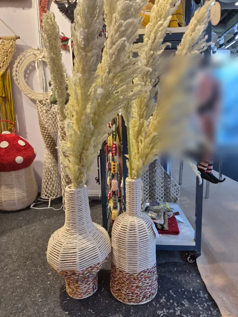 Two tall woven vases holding pampas grass beside a red and white crochet mushroom stool, at our stall, IHGF Delhi Fair Autumn 2026.