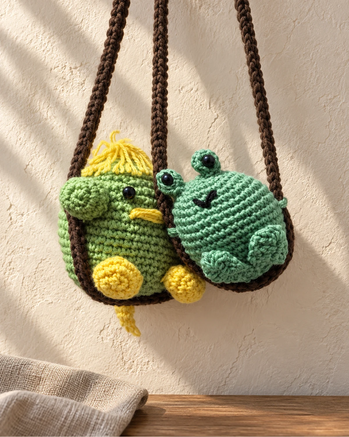Two crocheted character bags with duck and frog faces.