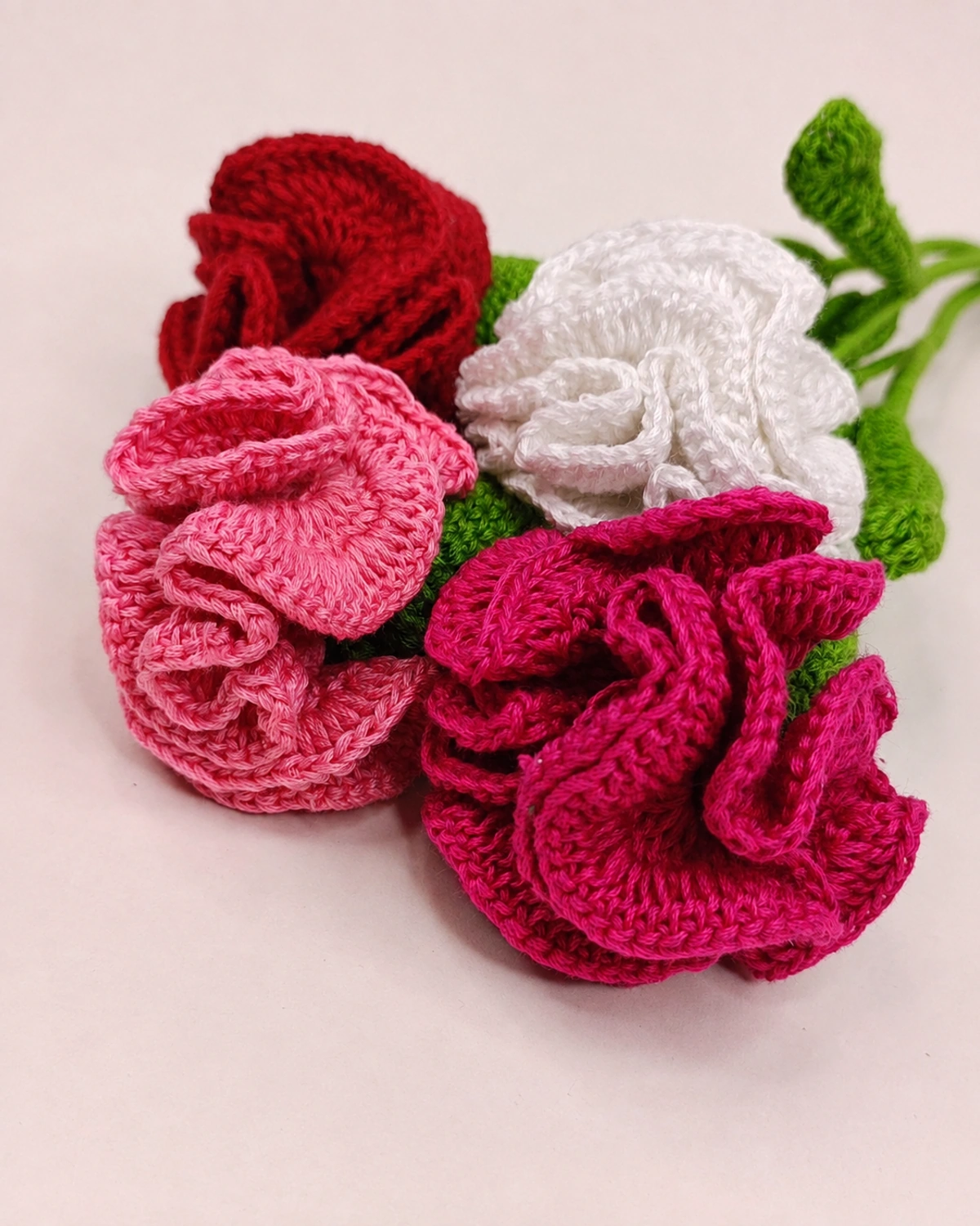 Close-up of crocheted roses in red, white and two shades of pink.