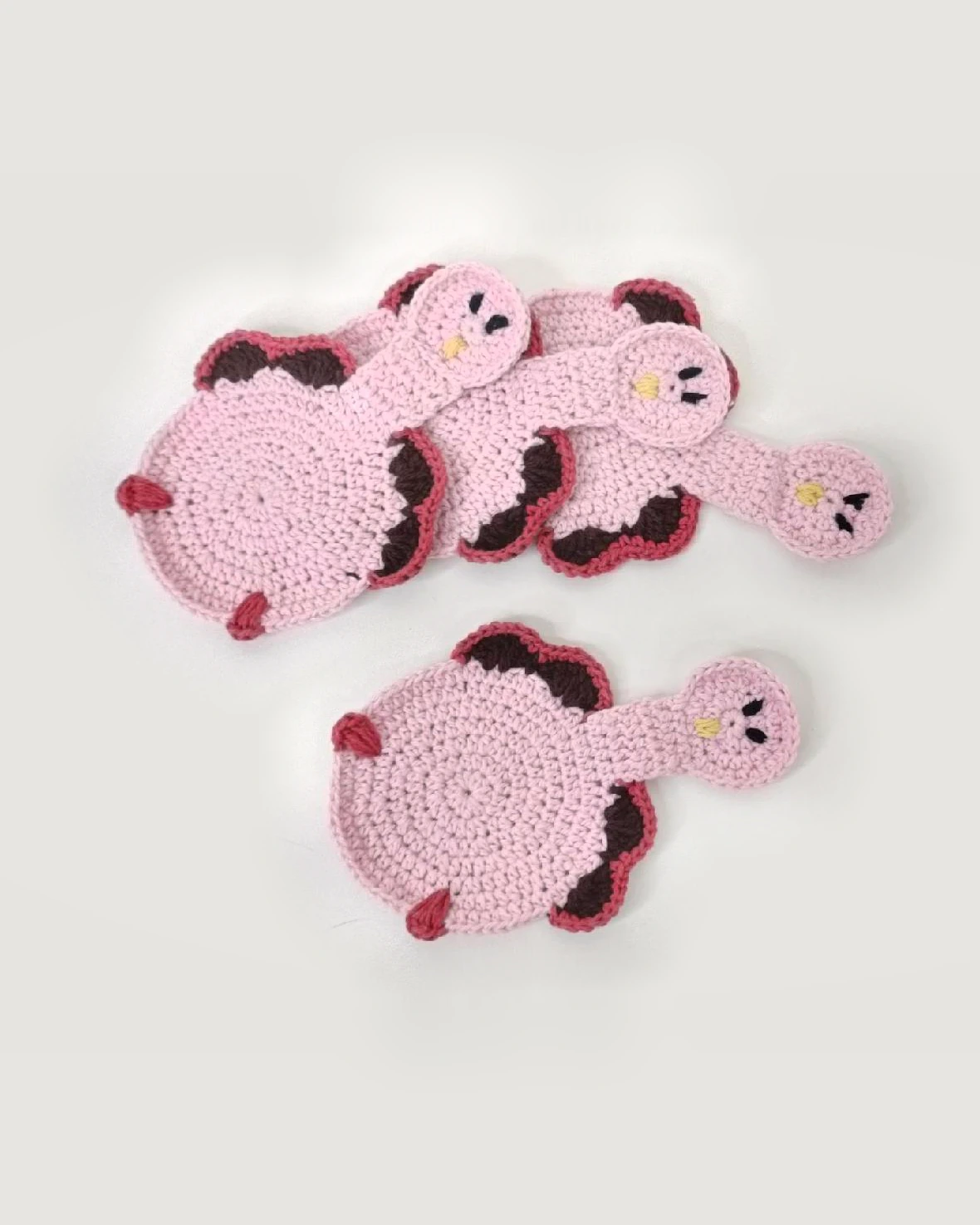 Four pink crocheted bird-shaped coasters with burgundy edging.