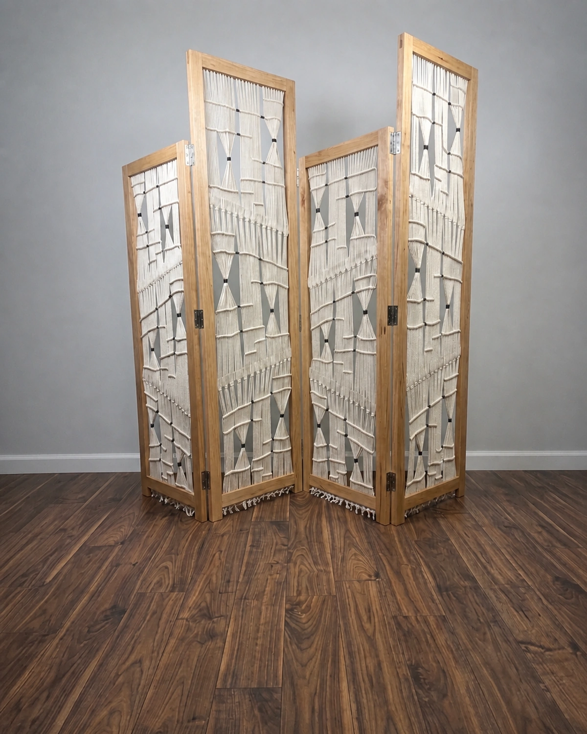 Four-panel wooden room divider with cream macramé and dark connecting details.