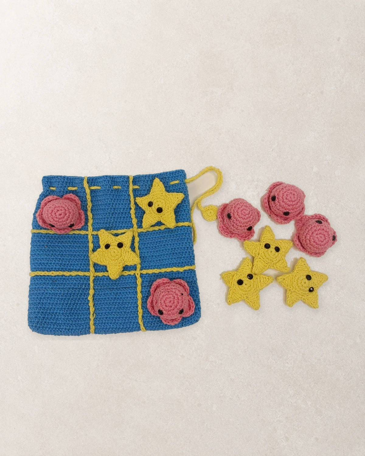 Blue crocheted set with pink and yellow crochet pieces and a drawstring bag.