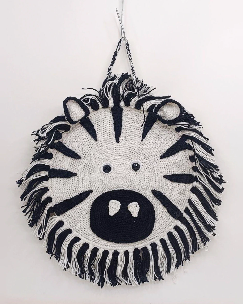 Round black-and-white crocheted zebra hanging.