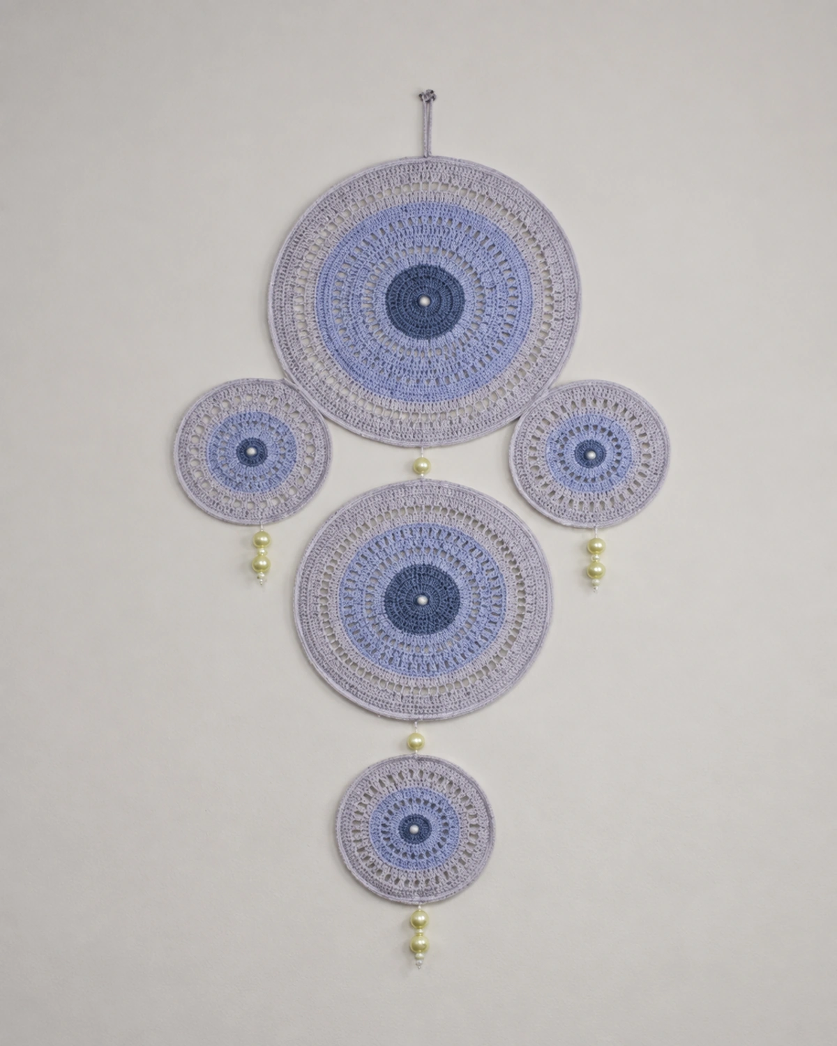 Vertical blue and grey crocheted wall hanging with linked circular forms.